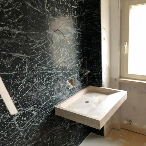 Lavabo in marmo su parete in marmo nero venato