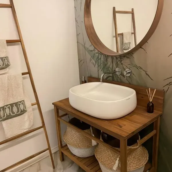 Bagno con lavabo su mobile in legno e specchio rotondo